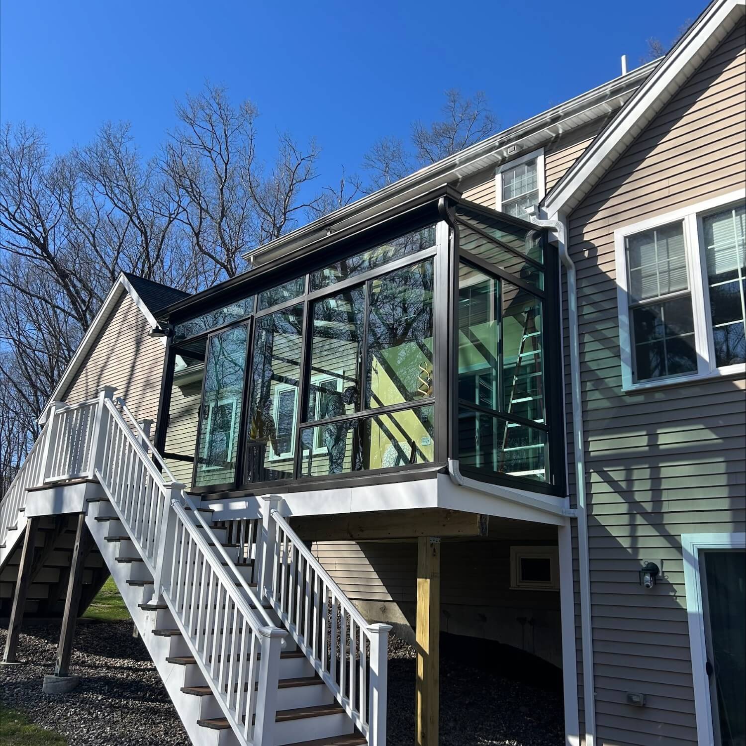 A second-story glass patio room with stairs leading up to it. 