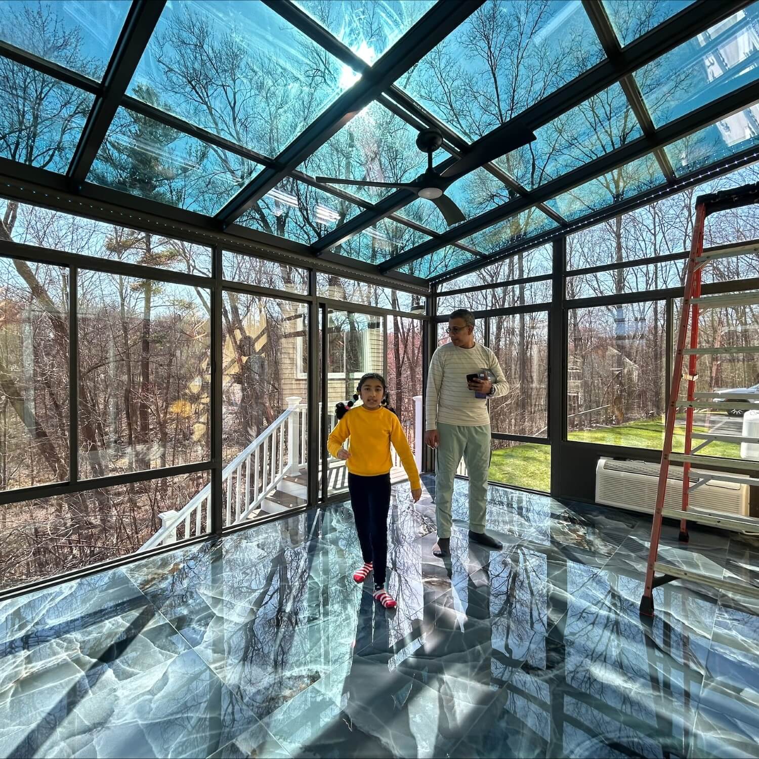 The interior of a patio room with a luxurious blue and green floor that complements the tinted ceiling glass.